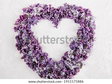 Lilac flowers in heart shape on the white background. Flat lay. Minimalist style. Close-up view