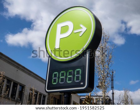 Low angle view of a lime green digital parking sign for a parking garage in a shopping district downtown