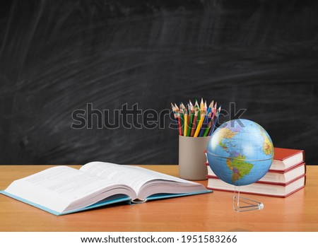 Drawn in chalk on a black school board with books, a globe on the desk