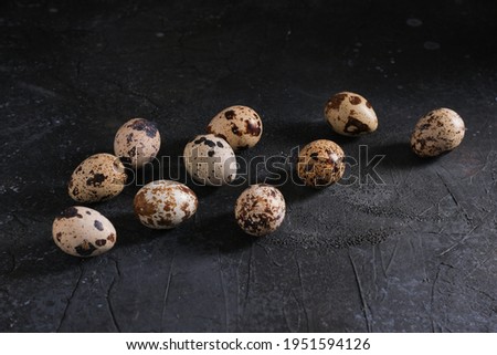 Small quail eggs are scattered on a dark background under the concrete, close-up. High quality photo