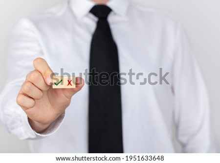 Businessman holding a check mark cube.
Right and wrong symbols. copy space white background.