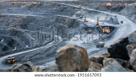 Work of heavy equipment in an open pit for gold ore mining, soft focus Royalty-Free Stock Photo #1951657093