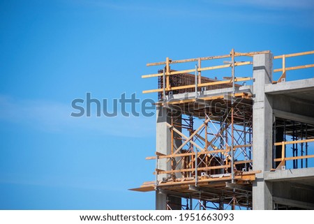 Upper floors of commercial concrete multi storey building with wooden scaffolding and guardrails during construction Royalty-Free Stock Photo #1951663093
