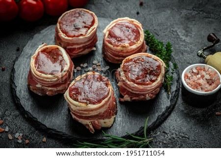 fresh raw fillet minion steaks wrapped in bacon served on a slate board, top view.