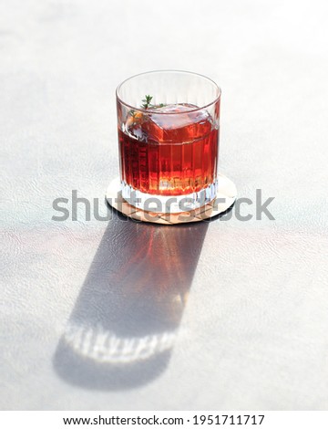 Italian Negroni Cocktail with sun shining through the glass and creating a long shadow. Royalty-Free Stock Photo #1951711717