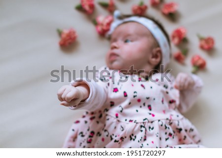 Toddler girl. Newborn. Lying down. Emotions. Top view. Scattered flowers.