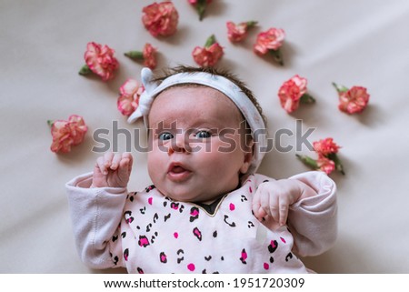 Toddler girl. Newborn. Lying down. Emotions. Top view. Scattered flowers.