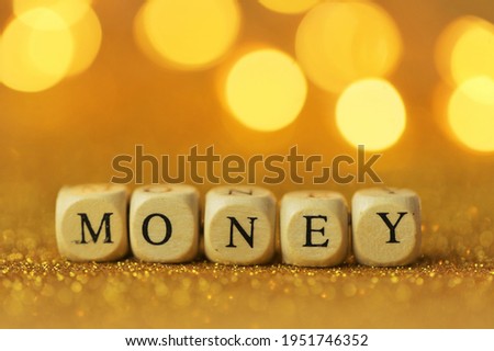 Money concept. Inscription money wooden letters on a gold glitter background with shining bokeh.Finance and business concept.