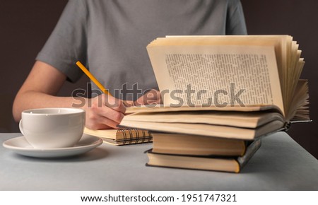 Female student hands underline information in book, prepare for exam, cup of tea or coffee, holding pencil. Education concept.