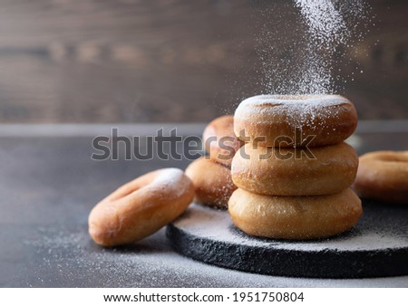 Sweet donuts with powder sugar on black background. Food concept. Copy space.