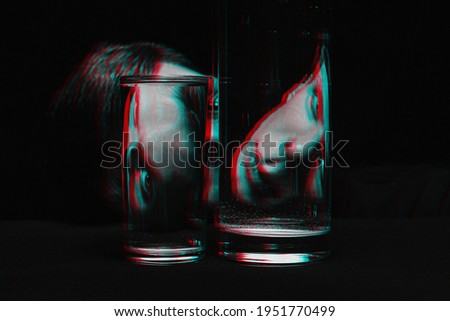 portrait of a man looking through two glasses of water