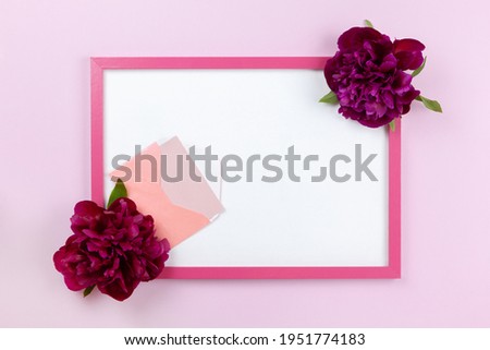 Pink rectangular frame with white center, peonies on sides, small envelope with card on pastel pink background, copy space. Flat lay, minimal style mockup. For gift shop, social media, website design.