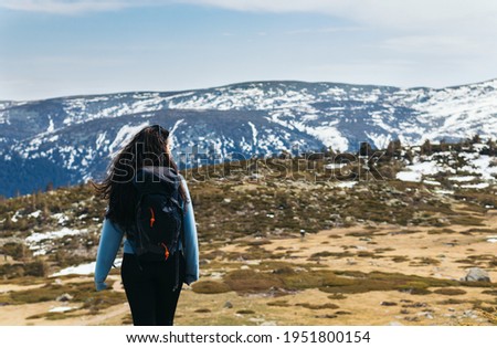 Back view of a young woman standing looking at mountain landscape. Winter landscape