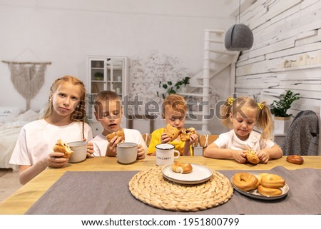 red children. 4 kids have breakfast. brothers and sisters eat chocolate croisans and drink tea.