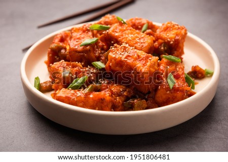 Crispy chilli paneer is a Indo Chinese starter or appetizer made by tossing fried cottage cheese in sweet sour and spicy chilli sauce, served in a plate. selective focus Royalty-Free Stock Photo #1951806481