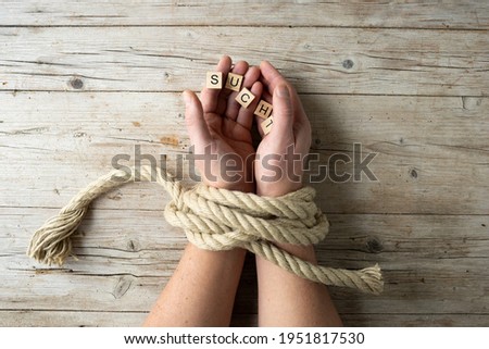 male hands are tied and hold letters with word addiction, concept addiction, photo taken from above