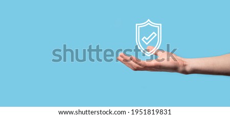 Male hand holding protect shield with a check mark icon on blue background. Protection network security computer and safe your data concept