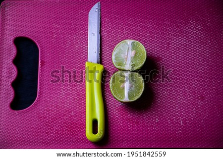 Stock photo of fresh juicy cut lemon kept on purple color chopping board with yellow color knife, focus on object. blur background.