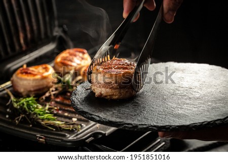 Cooking beef steak on grill pan by chef hands on black background for copy space text restaurant menu,