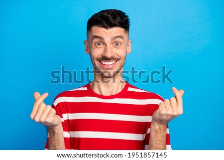 Photo of happy charming positive man make money sign fingers smile isolated on blue color background