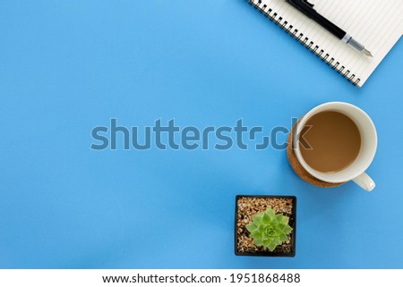 Top view notebook with coffee cup and cactus isolated on blue background with copy space
