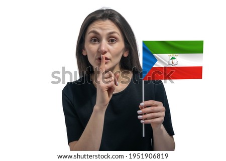 Happy young white woman holding flag of Equatorial Guinea and holds a finger to her lips isolated on a white background.