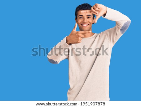 Young african amercian man wearing casual clothes smiling making frame with hands and fingers with happy face. creativity and photography concept. 