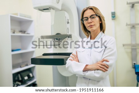 Cute professional woman doctor is working with modern Mammography X-Ray System Machine in a hospital or private clinic. Cancer and disease female treatment concept

