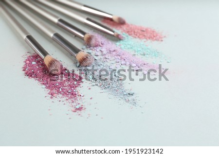 Different makeup brushes with crushed cosmetic products on light background. Space for text