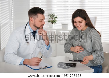 Pregnant woman with ultrasound picture at doctor's appointment in clinic