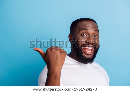 Portrait of cheerful excited man indicate thumb empty space over blue background