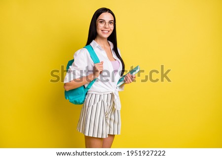 Photo of charming pretty happy young woman hold notebook wear bag isolated on yellow color background