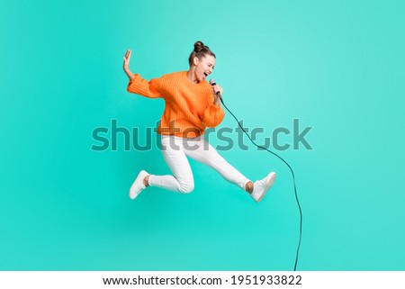 Full size profile side photo of young crazy screaming girl jumping singing in microphone isolated on turquoise color background Royalty-Free Stock Photo #1951933822