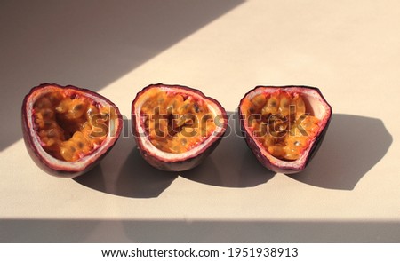 passion fruit cut into halves with a shadow on a lilac background