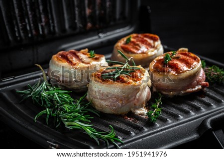 Medallions steaks from the beef tenderloin covered bacon on grill on Dark background. Top view.