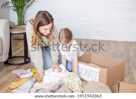 woman with daughter are sorting  clothes and wanna give some things to charity.