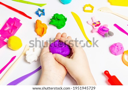 Children hands playing with colorful modeling clay on white background. Educational game with clay. Children sculpting figures from clay. Early development concept, close up