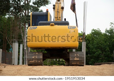 The backhoe's steel yellow colour on iron, parked on the ground in a construction site.