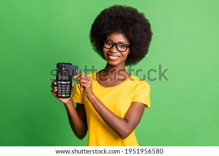 Photo of young cheerful beautiful afro girl using credit card on terminal cashless payment isolated on green color background