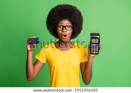 Photo of brunette wavy haired afro american woman amazed hold credit card reader isolated on green color background