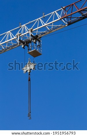 Details of the construction crane against the background of blue sky. Crane chain and pulley system. Photo taken on a sunny day.