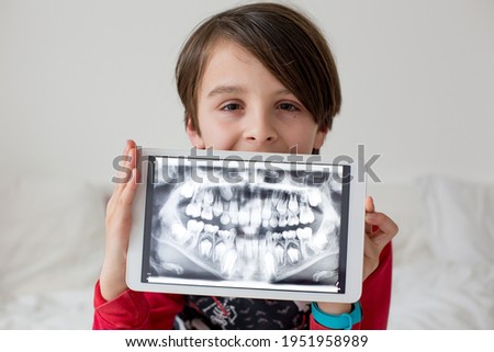 Child, preteen boy, holding tablet with a picture of his x-ray teeth from the dentist Royalty-Free Stock Photo #1951958989