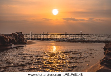 beautiful yellow sunset on the baltic sea under blue sky with white clouds on the sandy beach focus on the horizon