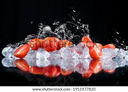 tomatoes water splash on a black background with ice cubes and crushed ice