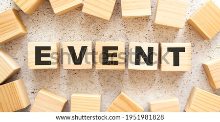 The word EVENT consists of wooden cubes with letters, top view on a light background. Work space.