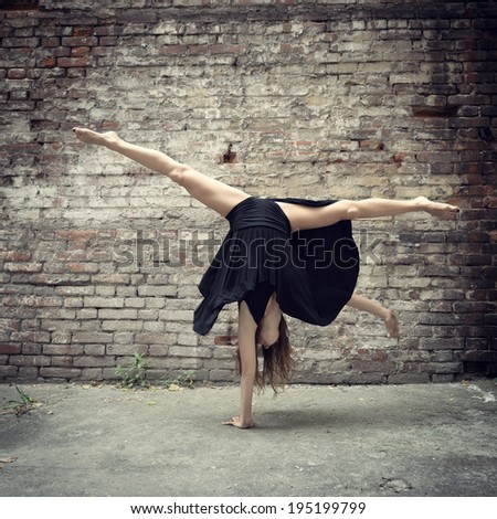 Attractive teen girl dancing outdoor against grunge bricks wall. Toned.
