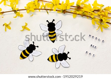Handmade paper bees with Forsythia flowers on white background. World Bee Day letter cubes. Craft for kids.