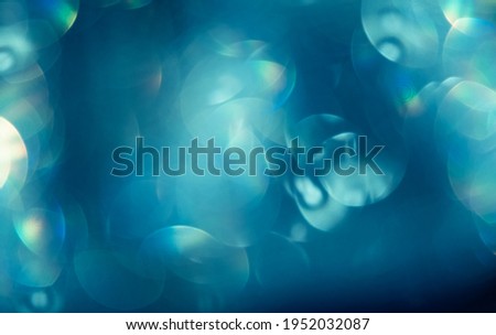 Abstract modern blurred rainbow circles on blue green background. Blurry light reflection bokeh made by a magic prism for psychology, 3d, nanotechnology, mobile technology and science concepts