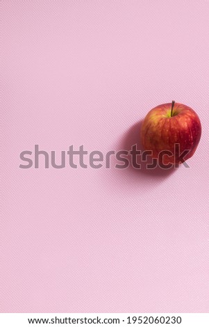 The vertical photo shows a picture of food. This apple is red in color. One apple. The apple is whole and in the skin