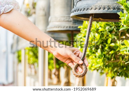 Woman hand rings the old bell for Make a wish in the Wat Saket Golden Mount Temple famous , is a Buddhist temple in Pom Prap Sattru Phai district, Bangkok. Royalty-Free Stock Photo #1952069689